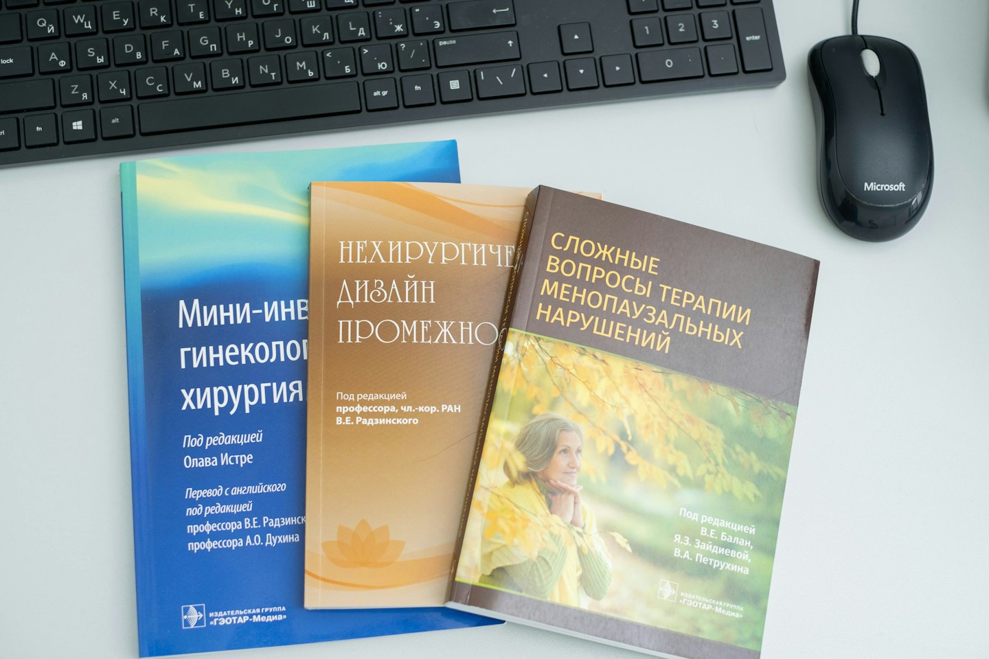 Three medical textbooks sit beside a keyboard and mouse.
